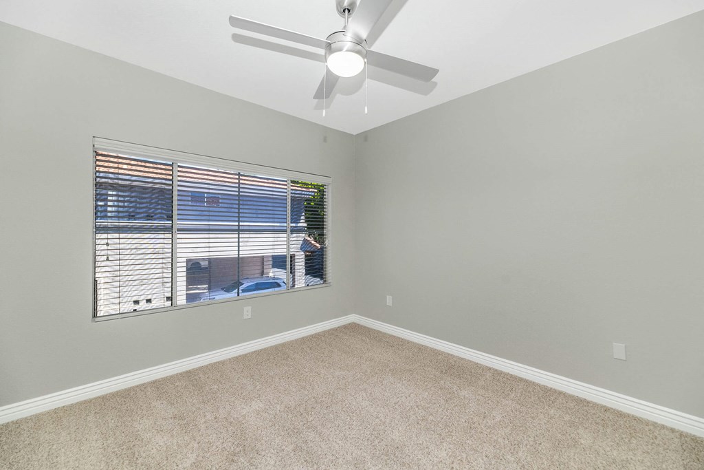 an empty bedroom with a large window and a ceiling fan