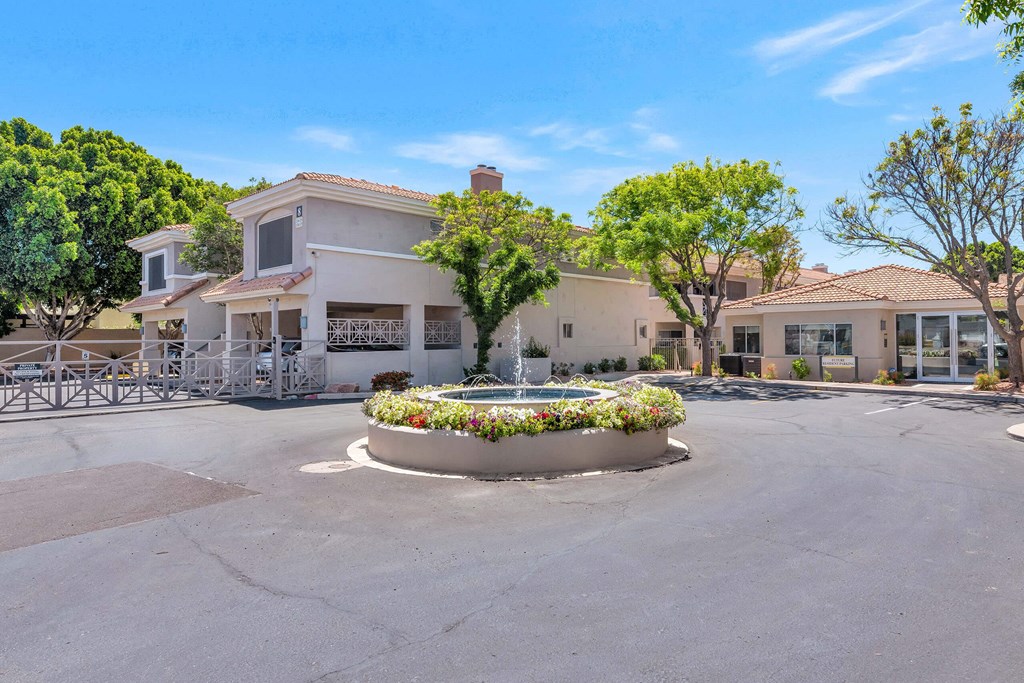 a fountain in the middle of a parking lot in front of a building