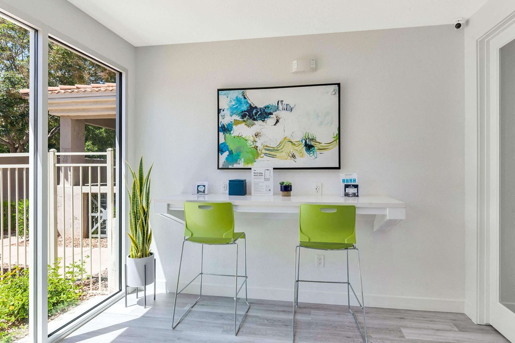 a home office with green chairs and a white desk and a painting on the wall