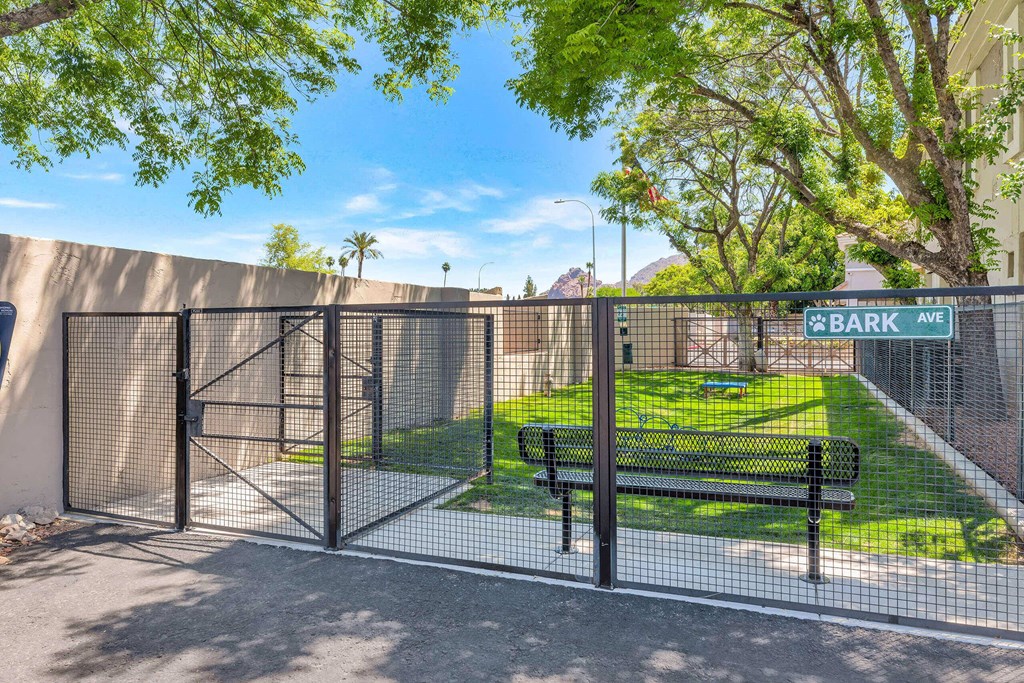 a gate to a park with a bench and a fence