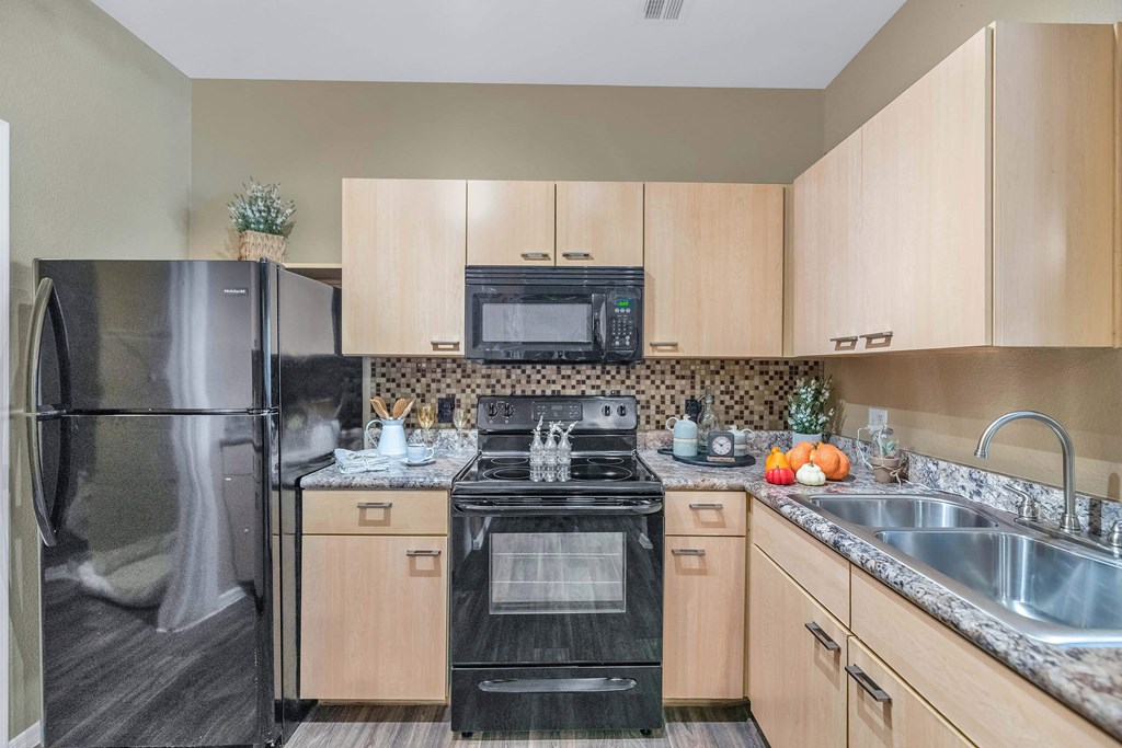 A kitchen with a black stove top oven and a black microwave above the stove  at Montage at Pecos Ranch Apartments, Chandler, Arizona