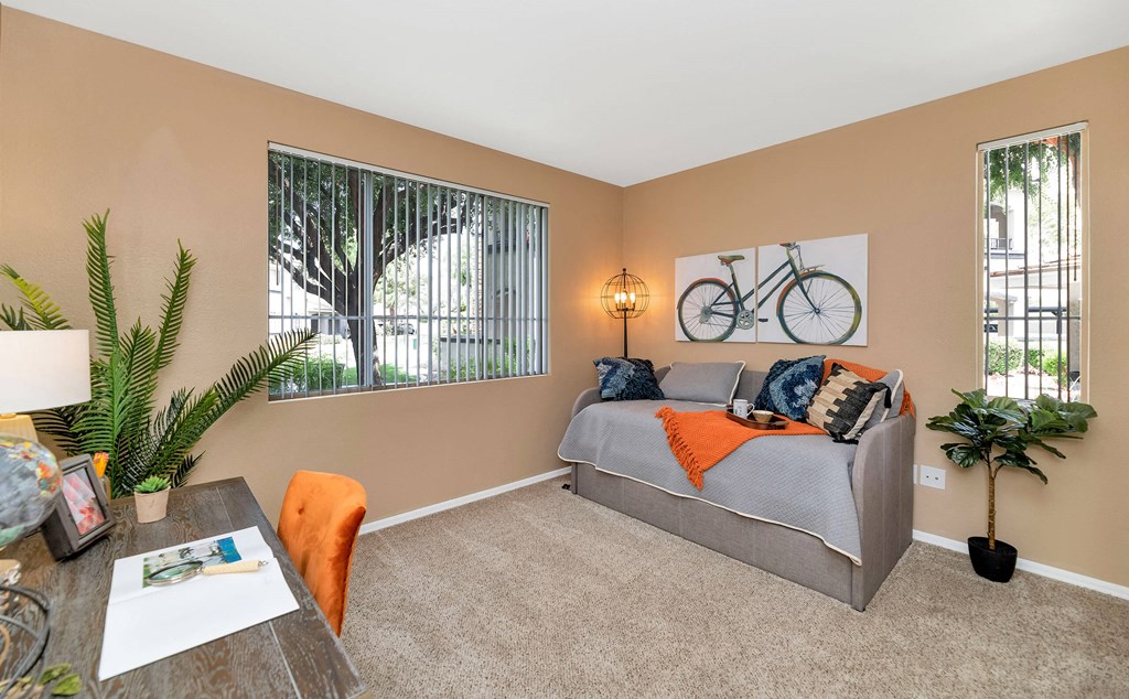 A living room with a grey couch, a wooden table, and a bicycle picture on the wall at Montage at Pecos Ranch Apartments, Arizona, 85286