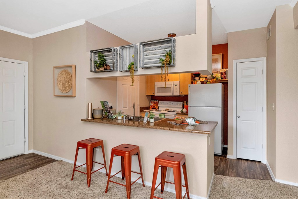 A kitchen with a white refrigerator, wooden countertop, and red stools at Montage at Pecos Ranch Apartments, Chandler, AZ, 85286