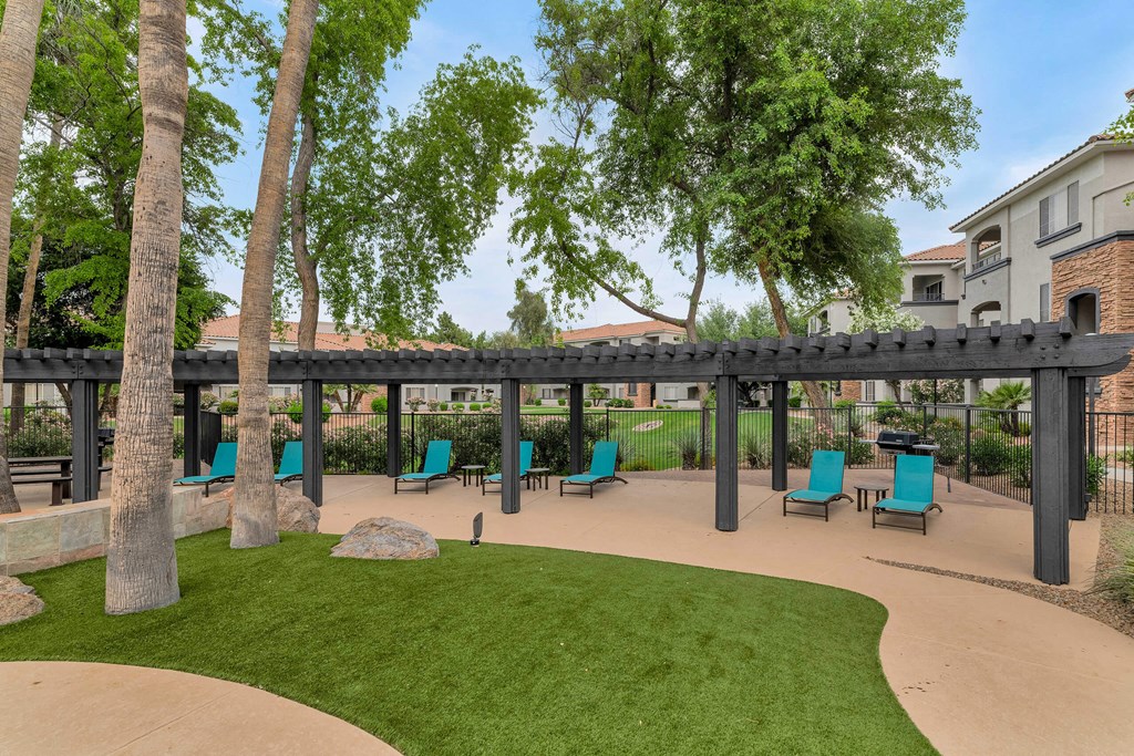 A patio with a black awning and blue chairs at Montage at Pecos Ranch Apartments, Chandler, AZ