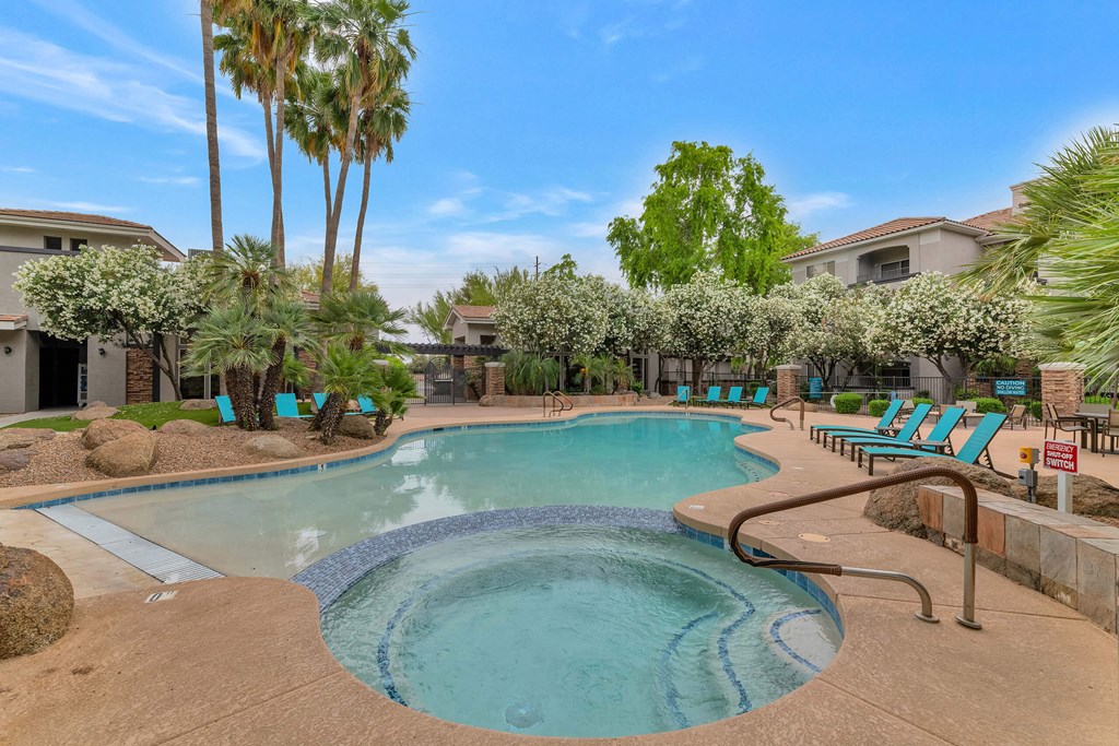 A swimming pool surrounded by palm trees and lounge chairs at Montage at Pecos Ranch Apartments, Arizona