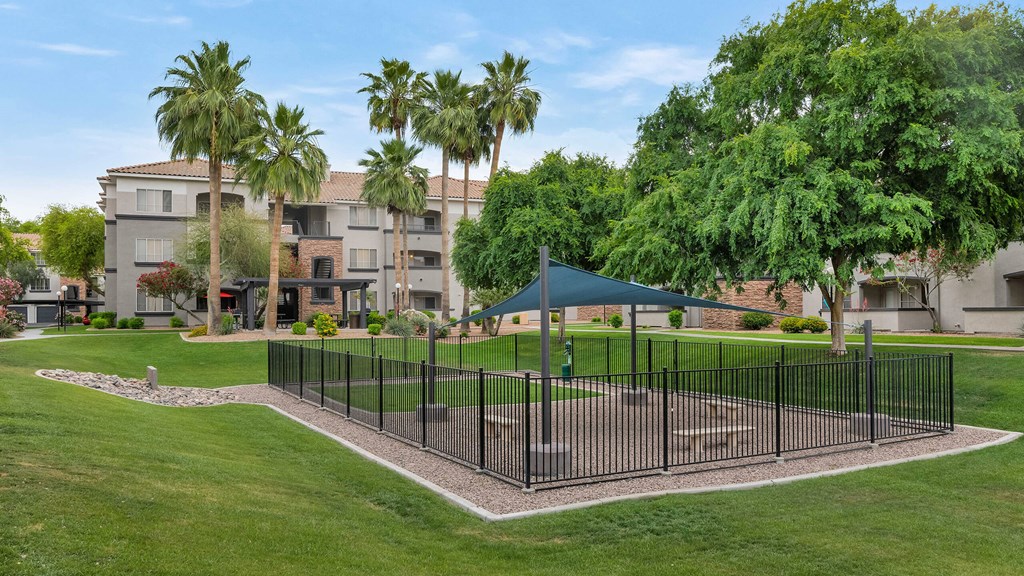 A black fence surrounds a green lawn in front of a building at Montage at Pecos Ranch Apartments, Chandler, 85286