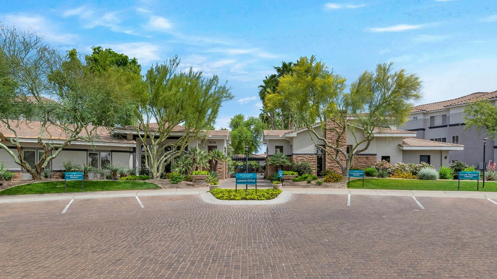 an empty parking lot in front of a building with trees at Montage at Pecos Ranch Apartments, Arizona