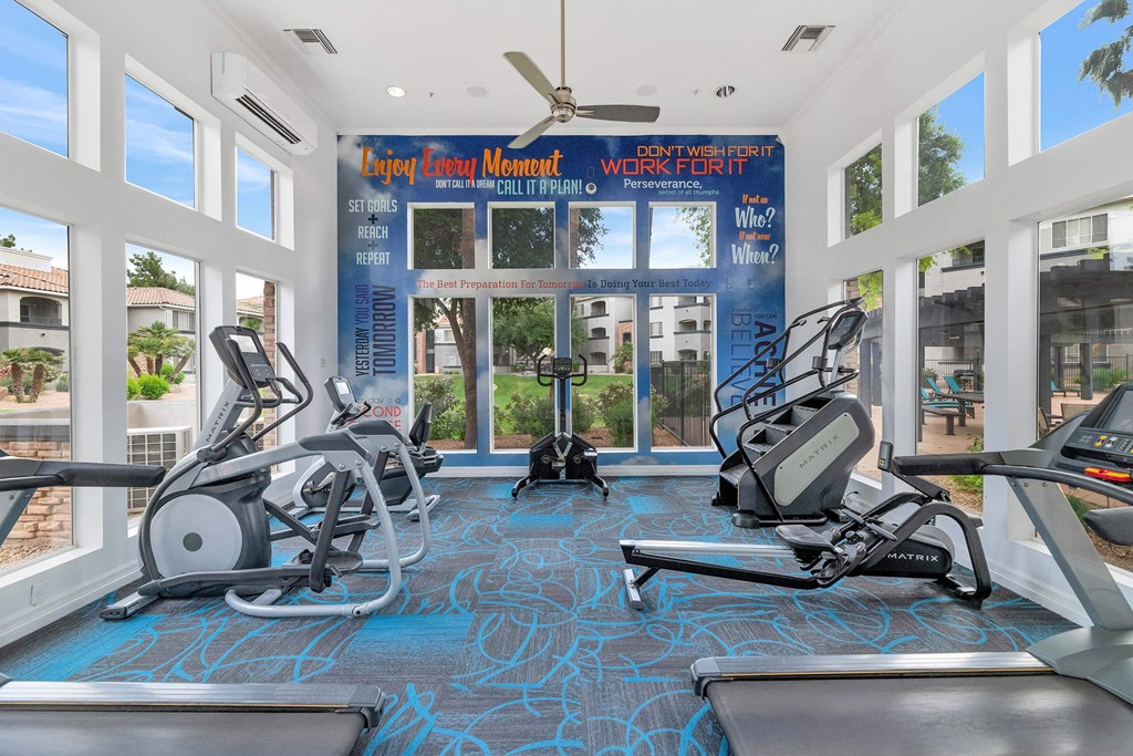 a gym with treadmills and weights in front of windows at Montage at Pecos Ranch Apartments, Chandler, Arizona