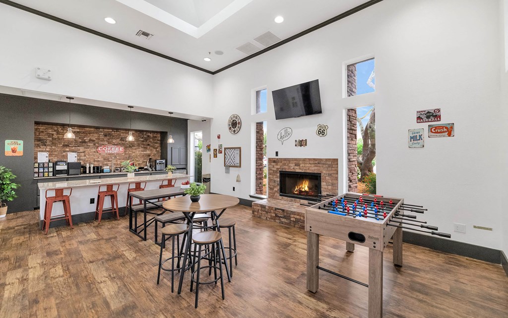 A room with a foosball table, bar stools, and a fireplace at Montage at Pecos Ranch Apartments, Chandler, AZ, 85286