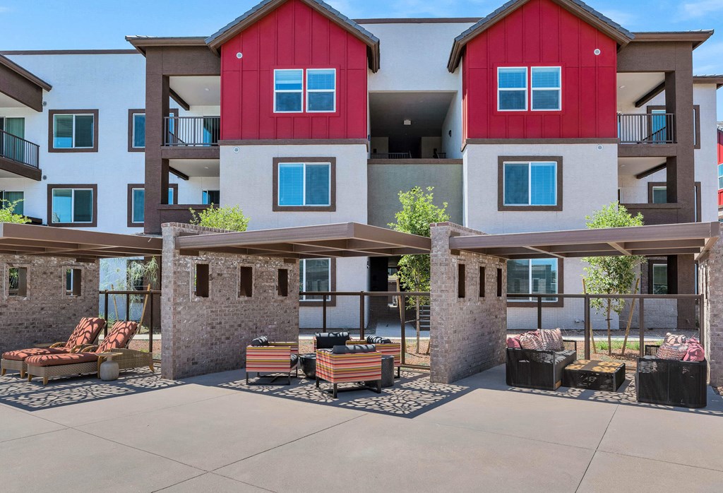 an outdoor patio with benches and tables in front of an apartment buildingat Weylyn Luxury Apartments, Laveen, AZ 85339