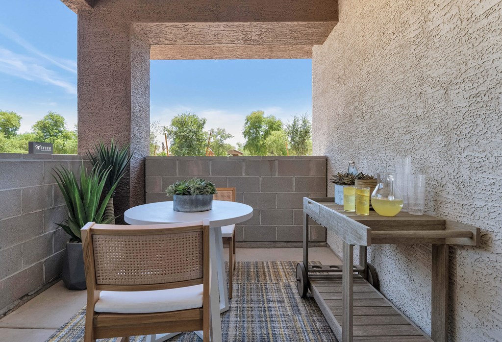 a patio with a table and chairs and a large window at Weylyn Luxury Apartments, Laveen, 85339