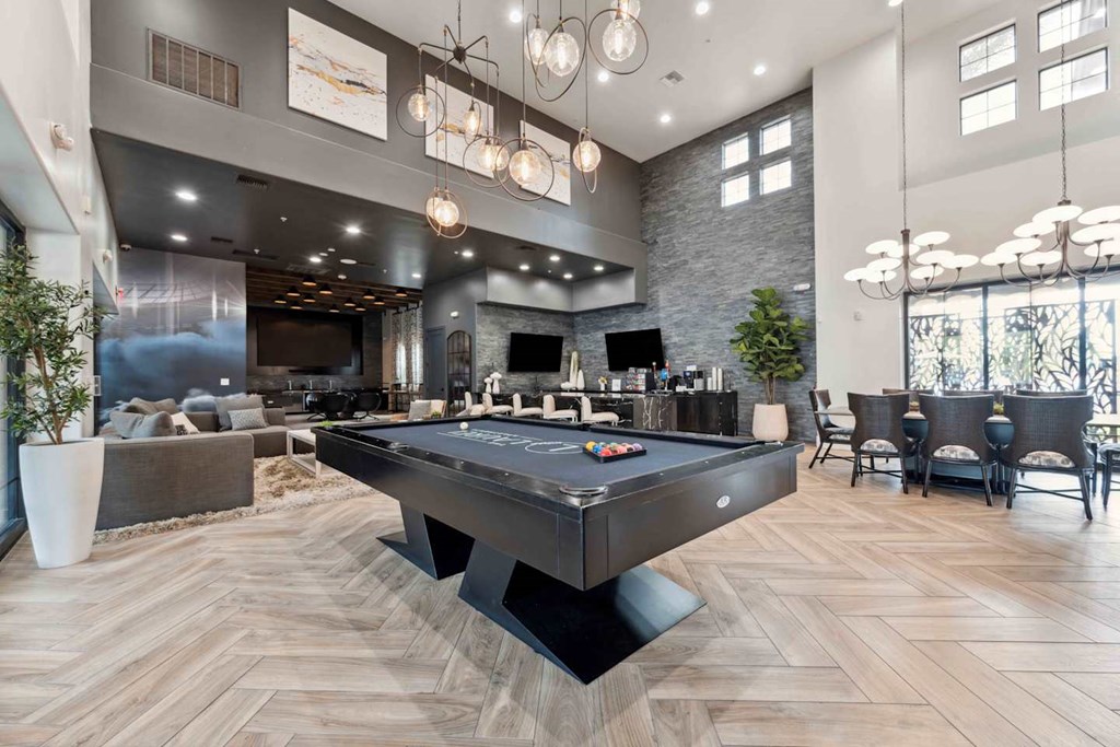 A pool table is in the middle of a room with a stone wall and a bar area. at The Laurel Apartments, Arizona