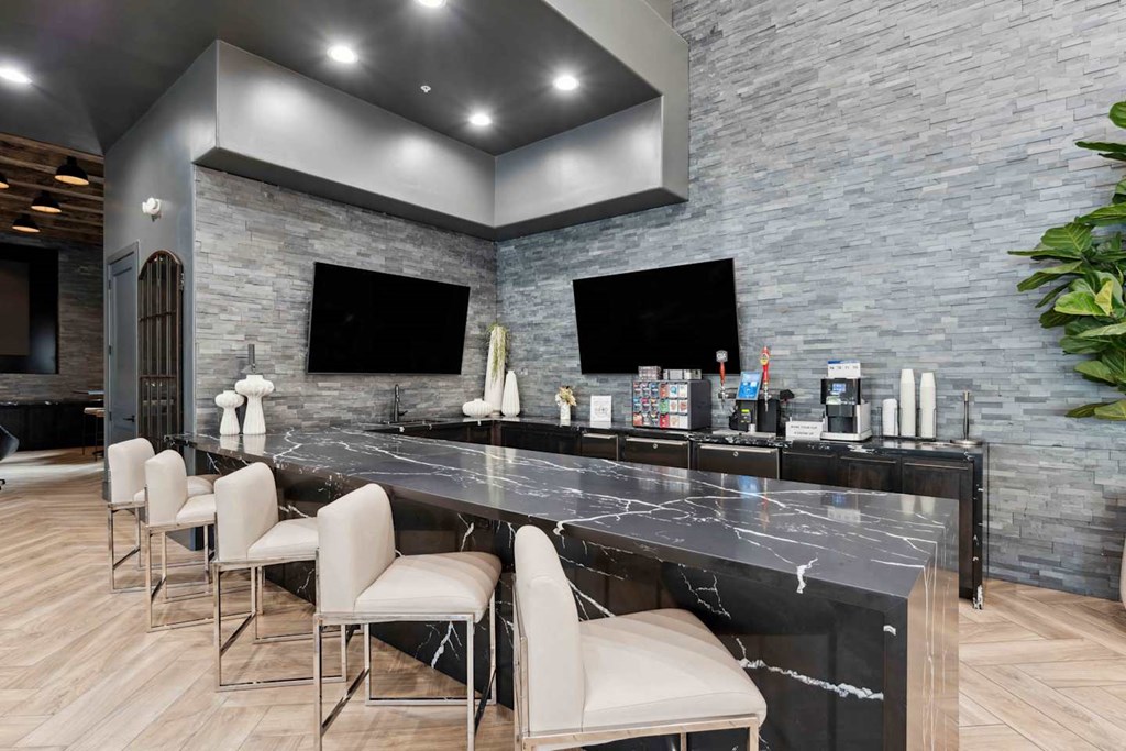 A modern kitchen with a marble countertop and bar stools at The Laurel Apartments, Arizona  .