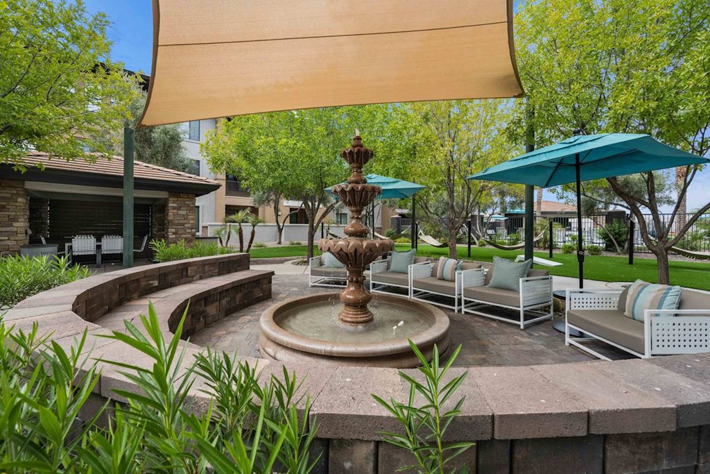 A fountain in the middle of a patio with a shade sail over it. at The Laurel Apartments, Chandler, AZ