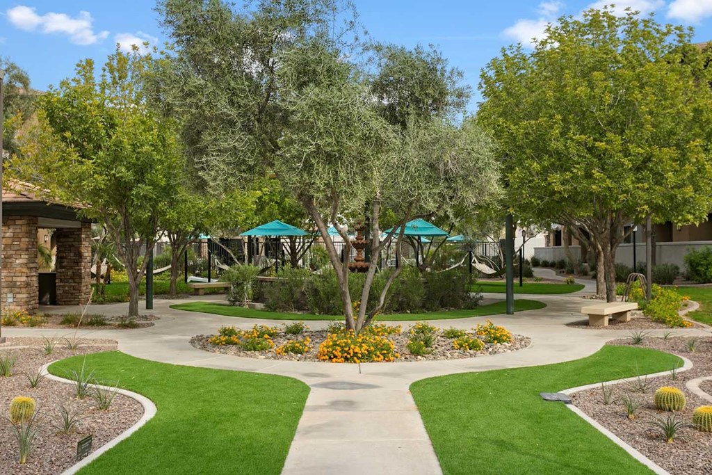 A garden with a circular flower bed in the center and a walking path around it. at The Laurel Apartments, Chandler, 85286