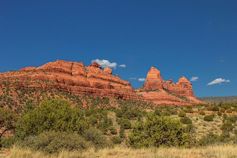 A large red rock formation stands out against a blue sky.