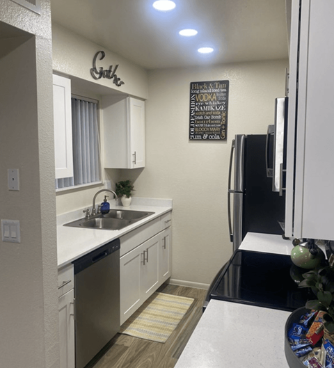 A kitchen with a white counter top and a black fridge.