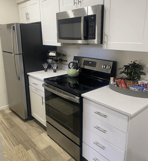 A kitchen with a black fridge, black oven, and white cabinets.