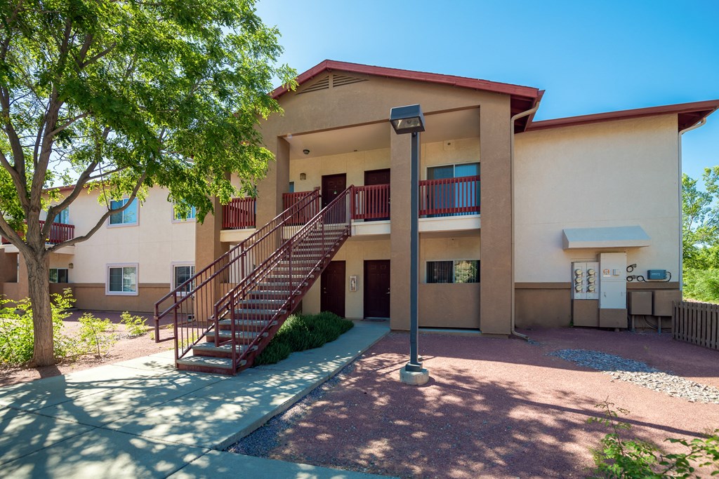 a building with a staircase and a tree in front of it