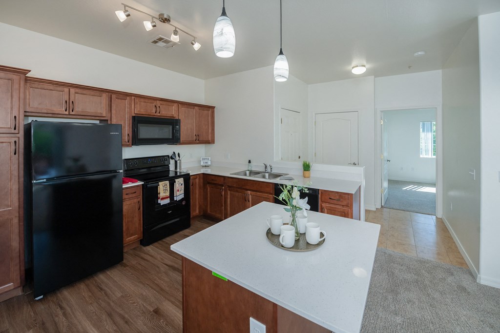 a kitchen with a white counter top and a black refrigerator