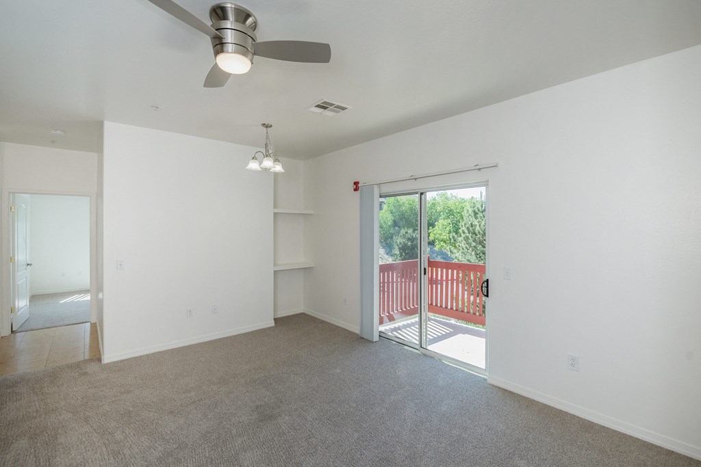 an empty living room with a sliding glass door to a balcony