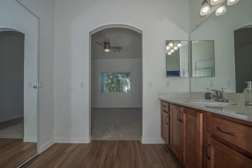 a bathroom with a sink and a mirror and a door into a room with a