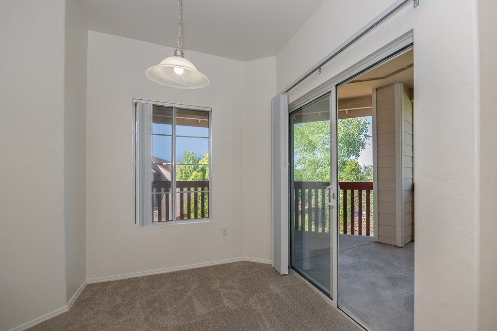 an empty living room with a sliding glass door to a balcony