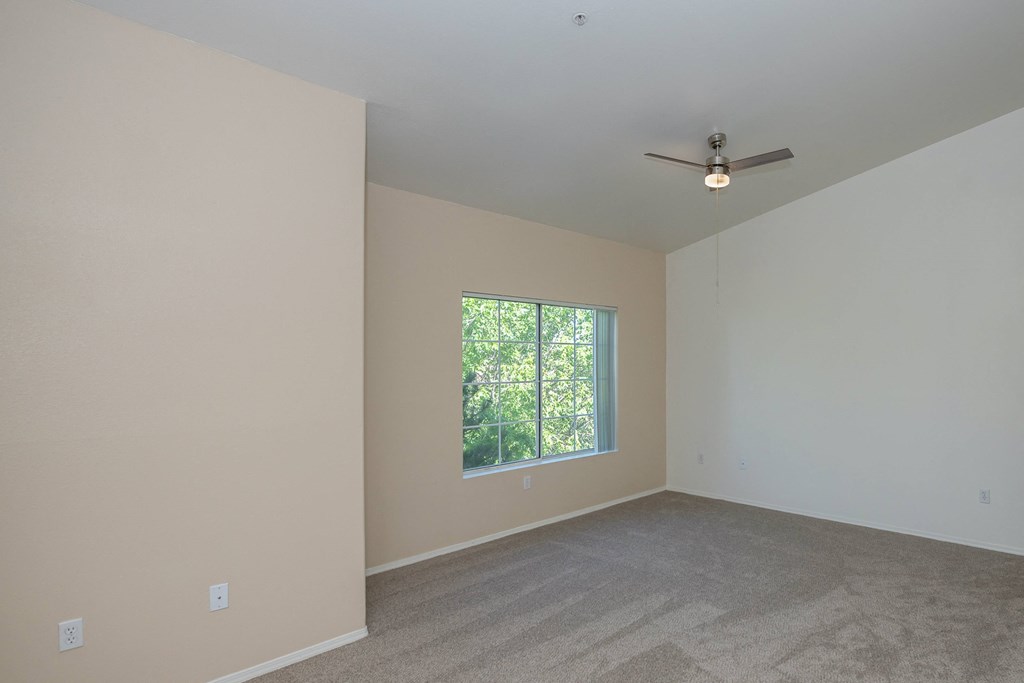 an empty room with a window and a ceiling fan