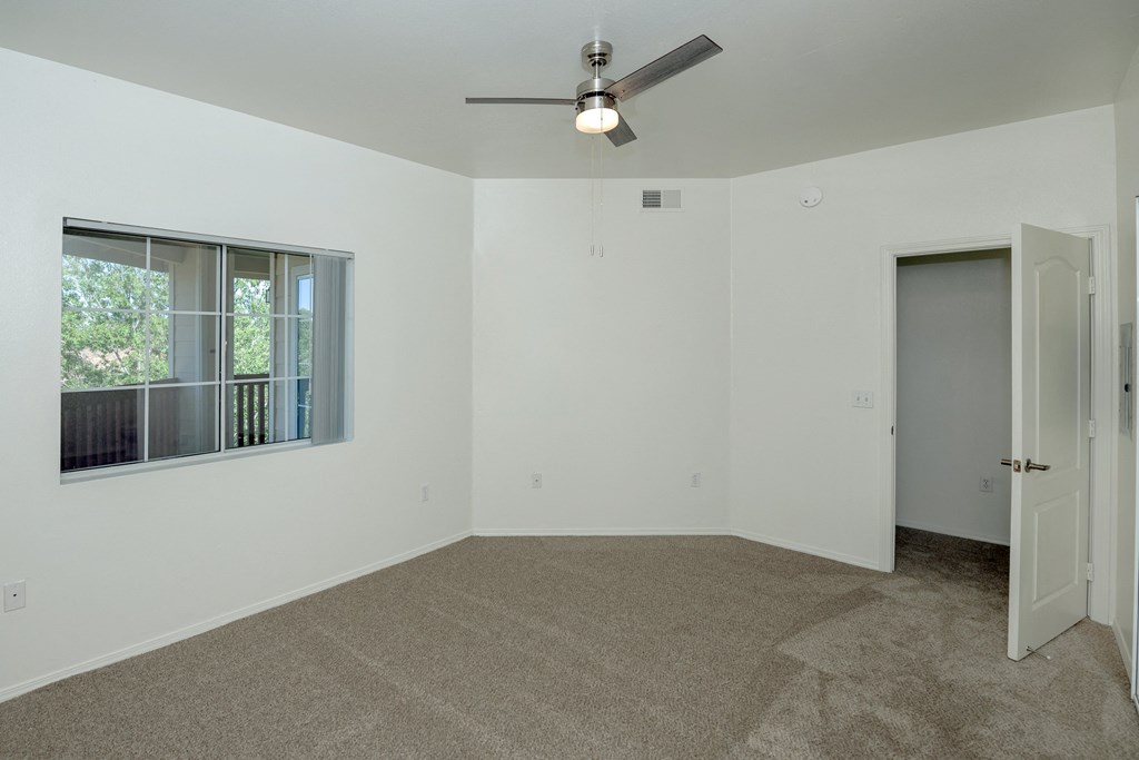 an empty room with a window and a ceiling fan