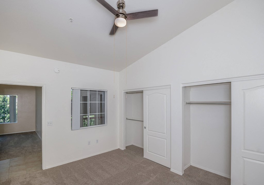 a living room with white walls and a ceiling fan