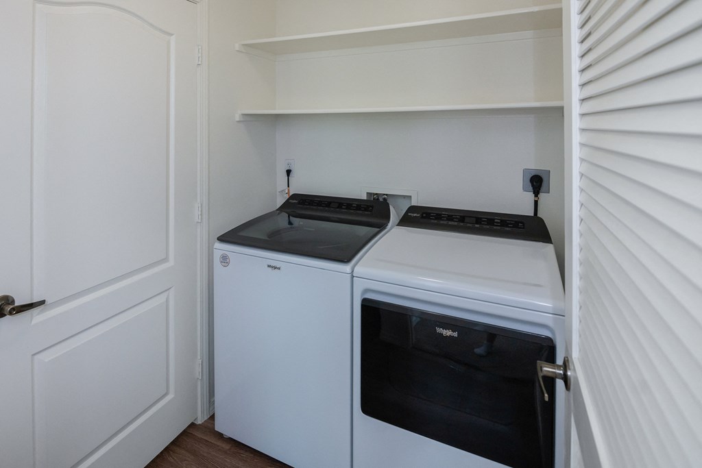 a white washer and dryer in a small room with a white door