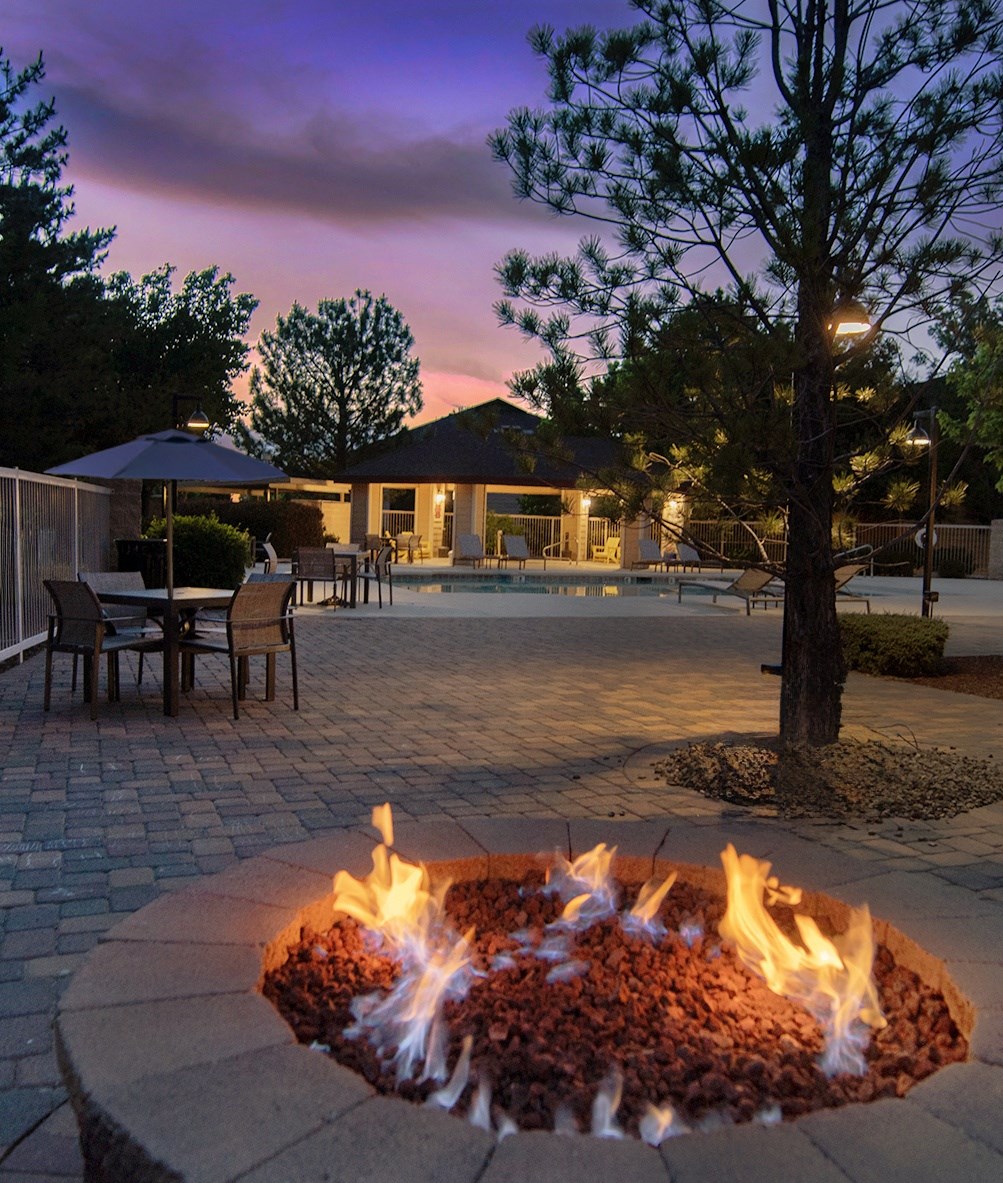 a fire pit in front of a pool at night