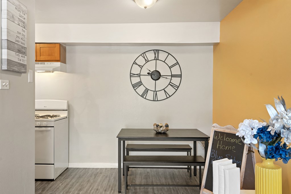 a dining area with a table and a large clock on the wall