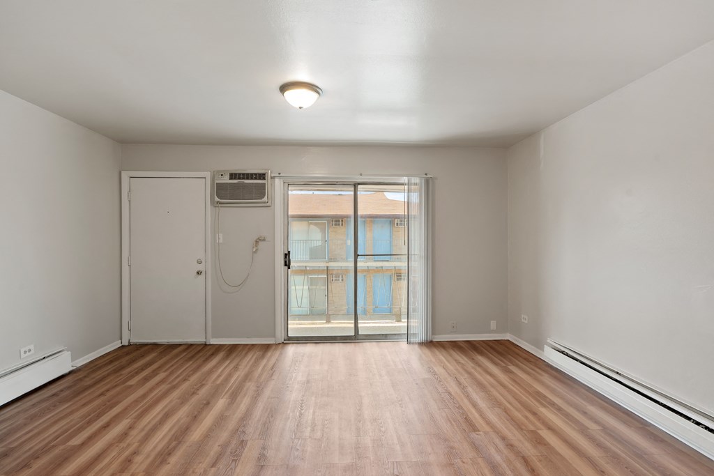 an empty living room with hardwood floors and a glass door leading to a balcony
