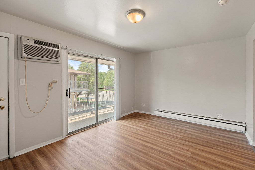a bedroom with a door to a balcony and hardwood floors