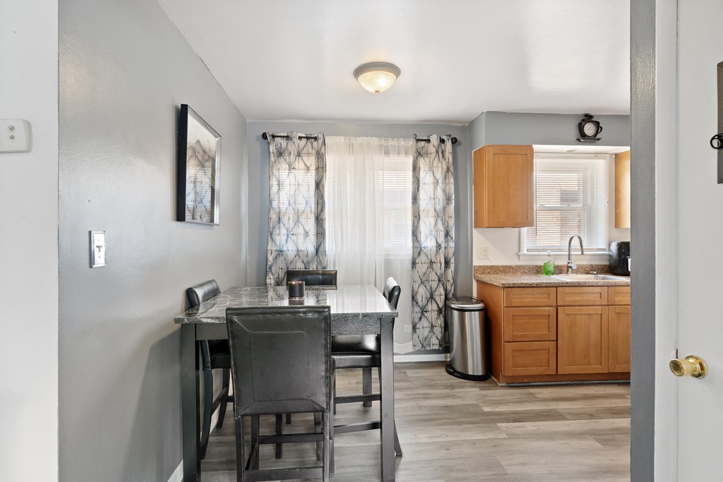 a dining area with a table and chairs and a kitchen in the background