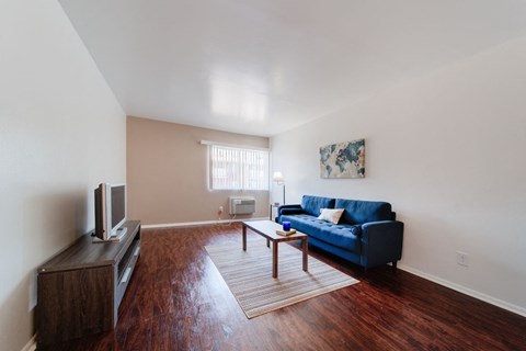 A living room with a blue couch and a wooden floor.