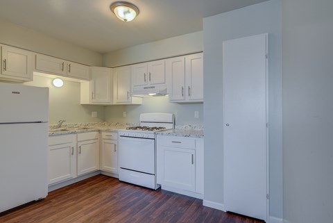 a kitchen with white cabinets and white appliances and a wood floor