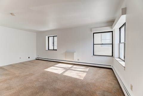 the living room of an apartment with carpet and windows