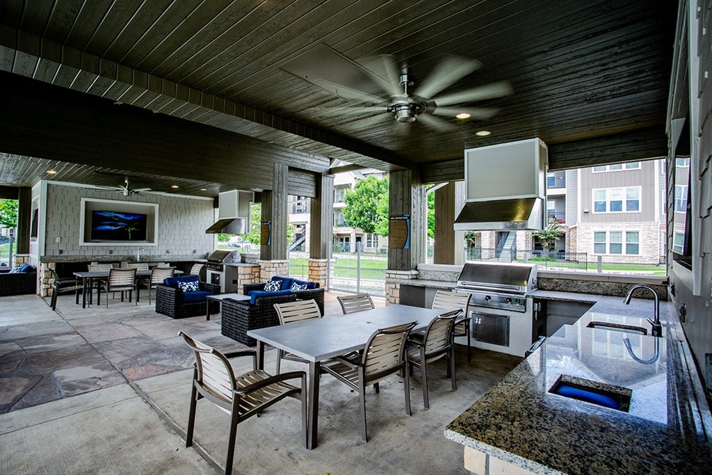 a covered patio with a kitchen and dining area