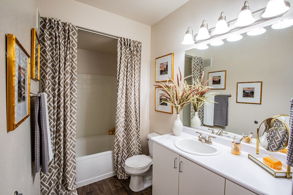 A bathroom with a white sink, toilet, and a mirror.