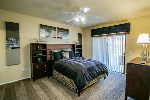 a bedroom with a bed and a window with a ceiling fan