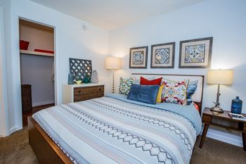 A bedroom with a large bed and a dresser with a mirror.