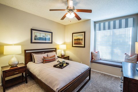 A bedroom with a bed, nightstand, and window seat.
