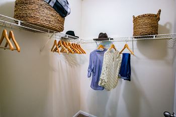 a walk in closet with white walls and a white shoe rack with yellow hangers