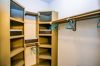 a walk in closet with wooden shelves and hangers