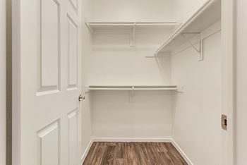 an empty closet in a home with white walls and wood floors