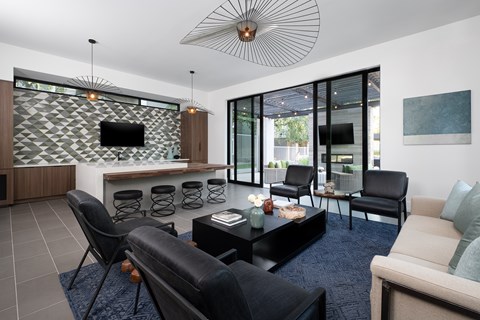 A modern living room with black leather chairs and a patterned wall.