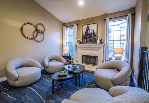 A living room with a fireplace and a painting of two horses.