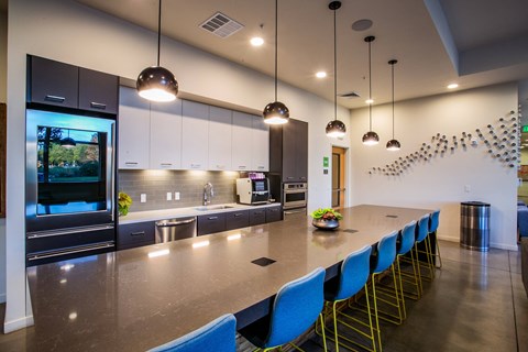 a large kitchen with a long counter and blue chairs